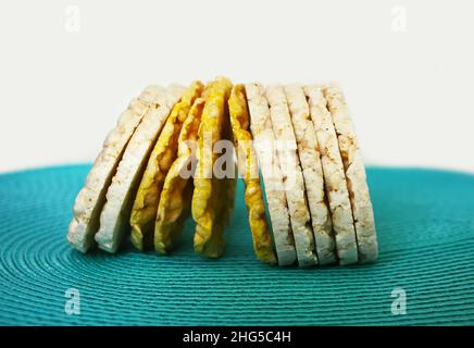 White and yellow flat round rice and corn crackers on blue background. Stock Photo