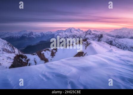 Snow covered mountains and purple sky with clouds at sunset Stock Photo