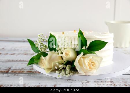 Beautiful wedding cake with white roses on white background. Stock Photo