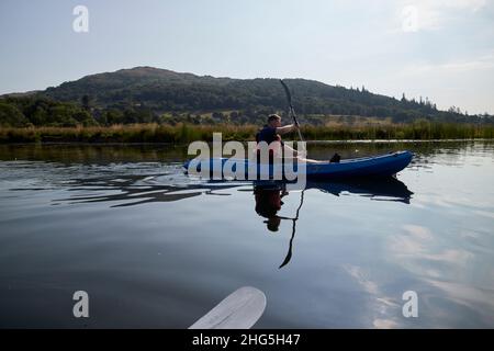 man paddling past other kayakers on early morning trip out lake windermere lake district, cumbria, england, uk Stock Photo
