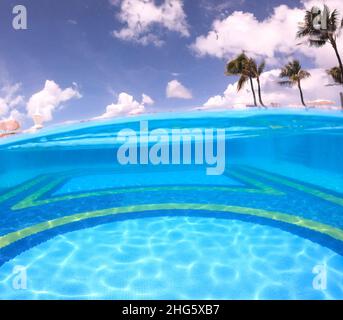 Split photo of an empty pool and blue sky with palm trees Stock Photo