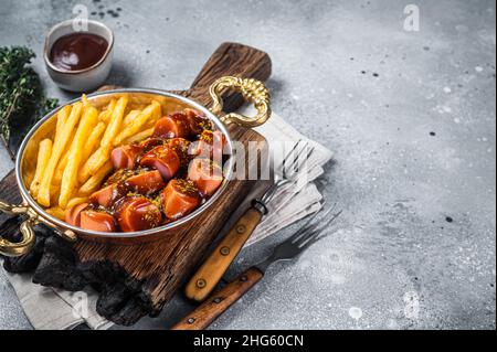 Traditional German currywurst sausage, served with chips or French fries in a pan. Gray background. Top view. Copy space Stock Photo