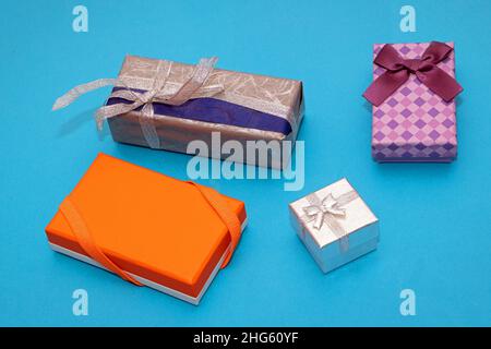 Beautiful colorful festive gift boxes with bows and silver glitter ribbon on blue background Stock Photo