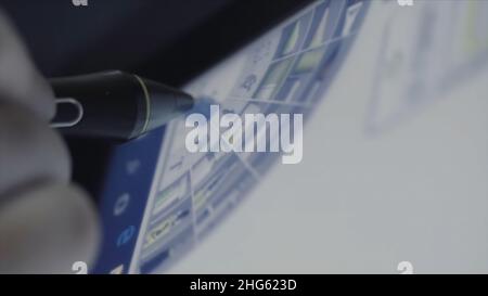 Graphic designer working with a tablet and stylus in the office. Close up of an artist drawing a portrait of long haired teenager. Stock Photo