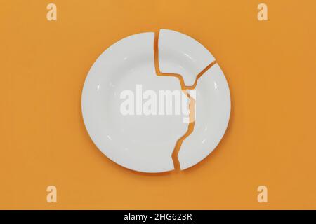 Top view on broken circle white plate on yellow background. The plate broke into three pieces. Concept photo. Stock Photo