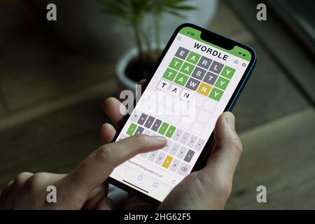 A woman plays Wordle on its official website on her iPhone on January 14, 2022. The word game developed by Josh Wardle has become the most recent social... Stock Photo