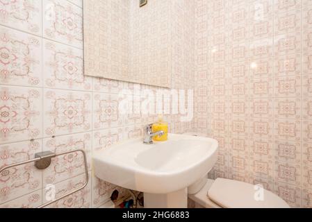 Bathroom with kitsch fixtures and tiles, white sink and square frameless mirror Stock Photo