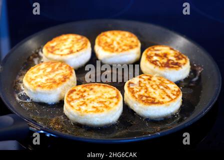 Cottage cheesecakes are fried in a frying pan. The process of cooking delicious homemade food. cheese pancakes or syrniki. Stock Photo