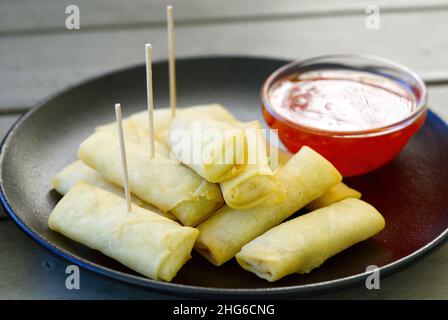 A plate of spring rolls with sweet chili dip sauce. outside restorante Stock Photo