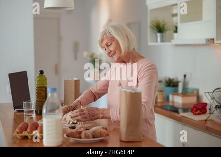 Smiling retired woman enjoying cooking at home Stock Photo