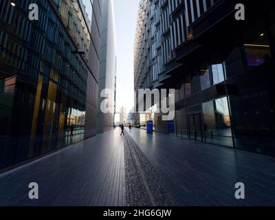 Tower Bridge and City Hall in the distant background on a winters morning with a walkway and modern buildings in the foreground, London. Stock Photo