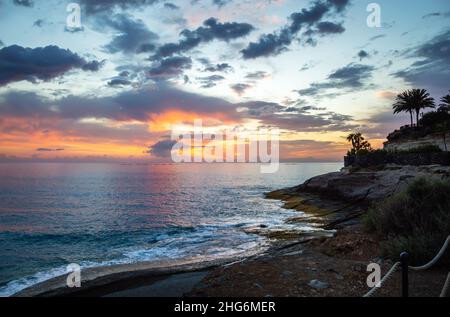 Dramatic sunset sky over ocean near Costa Adeje beach and Playa El Duque on Tenerife island in Spain. Last sun rays on cloudy sky over Canary islands Stock Photo