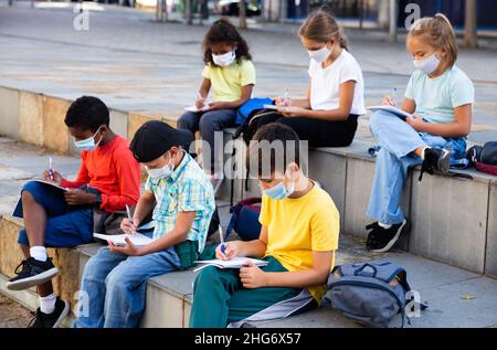 Kids wearing protective masks studying outdoors Stock Photo