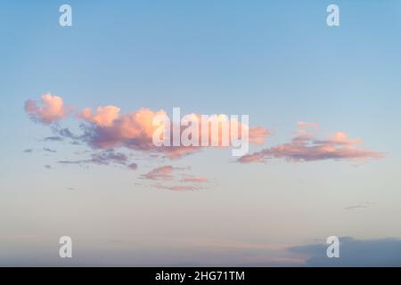 Beautiful sunset clouds in sky at White Sand Dunes National Monument in New Mexico with blue background and pastel pink and yellow sunlight Stock Photo