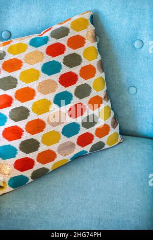 Closeup abstract vertical view of turquoise blue teal colorful sofa armchair chair with colorful multicolored pillow design with red and yellow colors Stock Photo