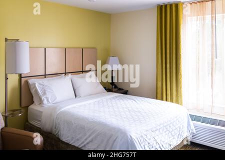 Bedroom room with lamps lights, white pillows with sheet on mattress bed headboard in modern hotel motel room with nobody and window curtains air cond Stock Photo