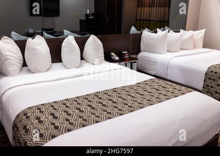 Bedroom room with two queen mattress beds in modern hotel motel room with white pillows sheets nobody and stylish decor interior design with mirror he Stock Photo