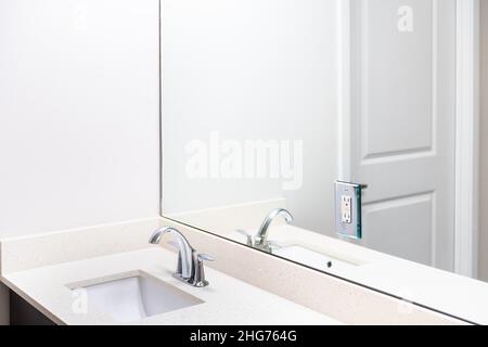 Modern white neutral interior design in bathroom house home or apartment with big large mirror reflection and vanity sink with chrome faucet fixture a Stock Photo