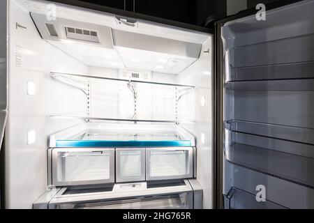 Interior closeup of empty modern luxury design French door fridge refrigerator with clean shelf shelves inside and no food Stock Photo
