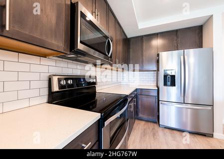 Nobody in modern luxury residential kitchen with tile backsplash quartz countertop by clean new fridge refrigerator stove oven and microwave appliance Stock Photo