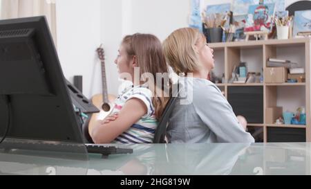 Mother and daughter standing back to back arguing for school grades. Annoyed worried parent fighting with child while sitting at desk in living room having difficulties. Concept of upset family Stock Photo