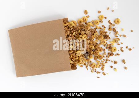 crunchy granola for breakfast, tasty granola poured out of paper bag isolated on white background, concept healthy food Stock Photo