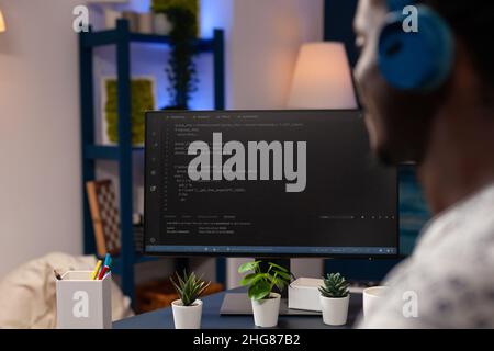 African american young developer programming software for website typing html code developing application. Businessman wearing headphones working at infographics javascript. Remote work from home Stock Photo