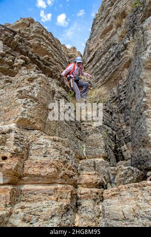 Woman descending cliffs on Moorina Bay along the Cape Queen Elizabeth track Stock Photo