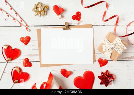 Flat lay of paper envelope with blank mockup greeting paper card. White wooden table background with Valentine day gift, letter, heart shape Stock Photo