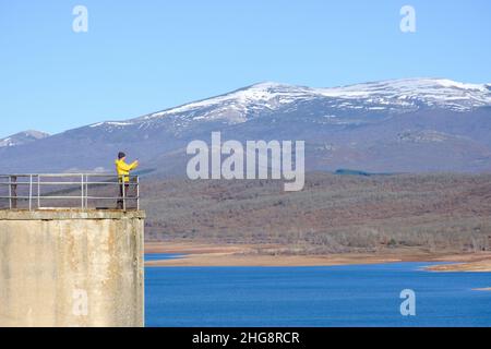 a man takes a picture with his smartphone from a lookout point above the lake Stock Photo