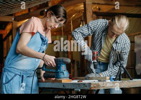 Man and woman working in workshop, doing furniture, reuse old materials to new product. awareness in consumption. Small family business. Recycling Stock Photo
