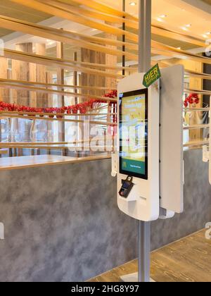 Basel, Switzerland - Dec 20, 2021: Empty restaurant in central basel no customers - new Mcdonald's self order kiosk fast food with POS system printer Stock Photo