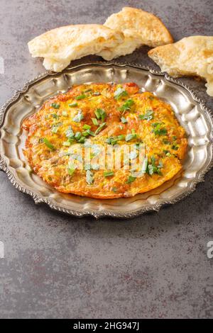 Indian food recipes Masala Omelette with fresh vegetables close up in the plate on the table. Vertical Stock Photo