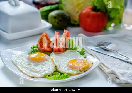 Fried eggs from two eggs on a plate with tomato Stock Photo
