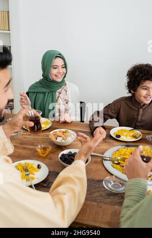 happy interracial muslim kids having dinner with blurred parents at home Stock Photo
