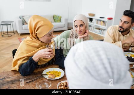 middle aged asian woman talking to muslim family during dinner at home