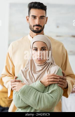 young arabian couple in traditional clothes looking at camera at home Stock Photo