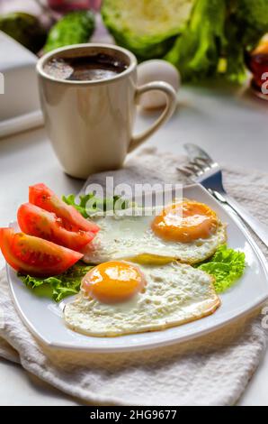 Fried eggs from two eggs on a plate with tomato Stock Photo