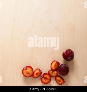 Whole, cored and sliced plums on wooden surface Stock Photo