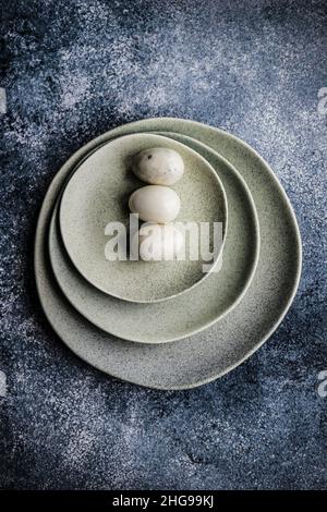 Overhead view of three Easter eggs on a stack of ceramic plates Stock Photo