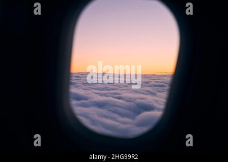 View from airplane window during flight above clouds at beautiful sunset. Stock Photo