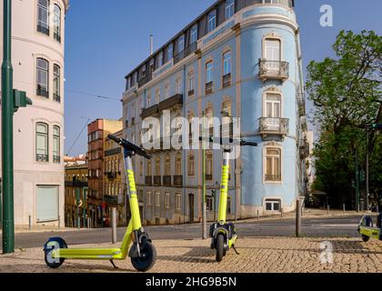 Lisbon, Portugal - Jul 10, 2021: Two electric scooters with LINK logo on sidewalk, no people, no cars. Summer, daylight, blue sky, old houses Stock Photo
