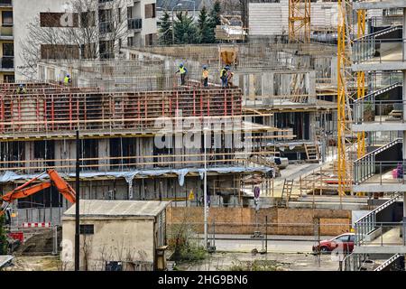 Construction workers install formwork and iron rebars or reinforcing bars for reinforced concrete partitions at residential building construction site Stock Photo