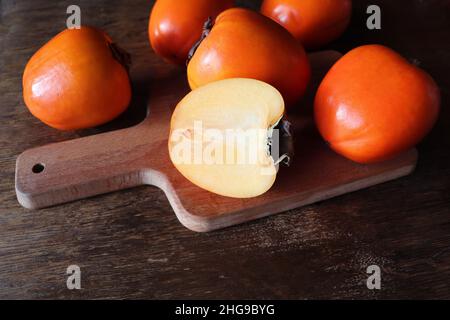 Fresh organic ripe Persimmons fruits with slice on old wooden table background. Top view. Flat lay. Copy space for text and content Stock Photo