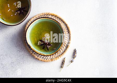 Overhead view of two cups of green tea with lavender and star anise on a place mat Stock Photo