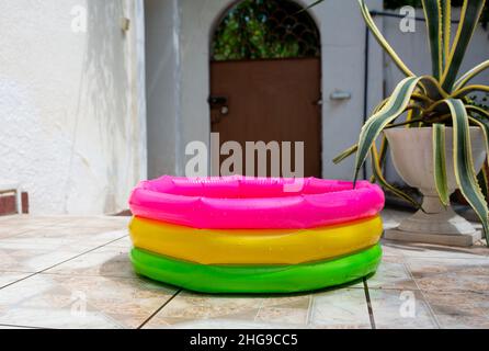Round rubber kids multi-colored inflatable pool in backyard in summer Stock Photo