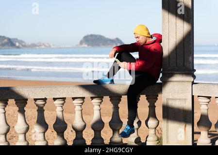 Young latin man using his phone and relaxing at seaside. Stock Photo