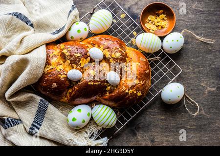 Traditional tsoureki Easter loaf with almonds on a cooling rack with painted Easter eggs Stock Photo