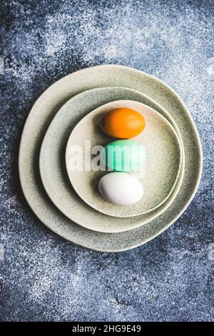 Overhead view of three painted Easter eggs on ceramic plates Stock Photo