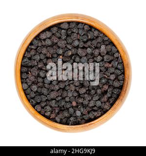 Dried bilberries, European blueberries, in a wooden bowl. Ripe and raw fruits of Vaccinium myrtillus, also known as blaeberry and wimberry. Stock Photo